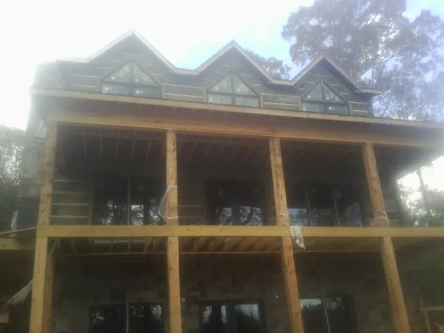 Dormers and porch framing on a large log home under construction — Roof Coating work by our crew in Carman