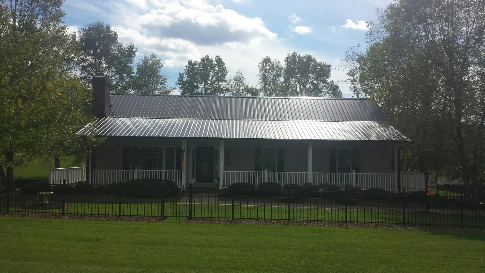 Gray metal roof on a brick ranch with a full width front porch — Gutter Guard Installation work by our crew in Carman