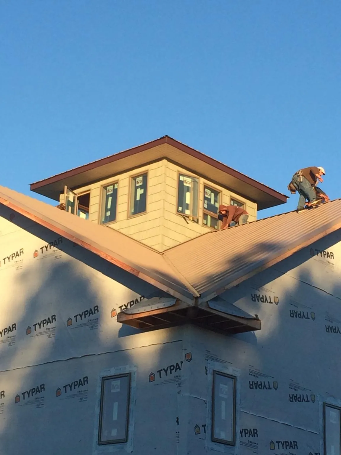 Roofers working around a rooftop cupola on a new metal roof at sunset — Roof Waterproofing in Carman by Roofing Brothers